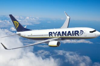 An image of a Ryanair aircraft mid-flight in the clouds.
