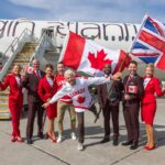 Sir Richard Branson, President of Virgin Atlantic, and airline staff gather in front of an aircraft with British and Canadian flags to celebrate.