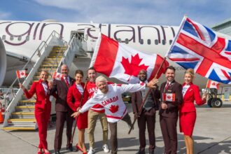 Sir Richard Branson, President of Virgin Atlantic, and airline staff gather in front of an aircraft with British and Canadian flags to celebrate.