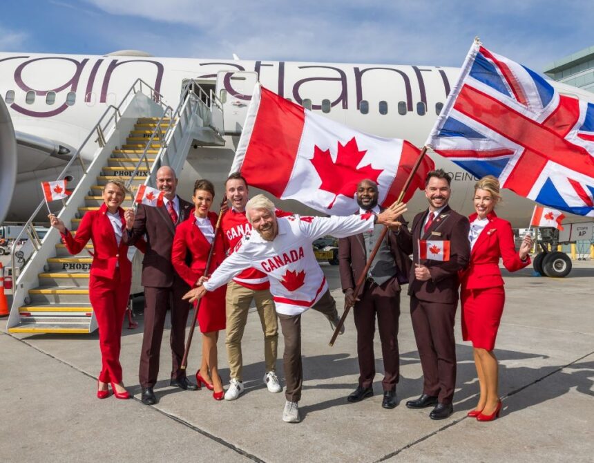 Sir Richard Branson, President of Virgin Atlantic, and airline staff gather in front of an aircraft with British and Canadian flags to celebrate.