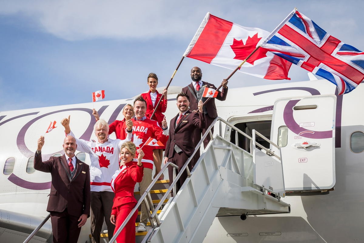 Sir Richard Branson and a team of staff from Virgin Atlantic celebrate on the stairs to an aircraft.