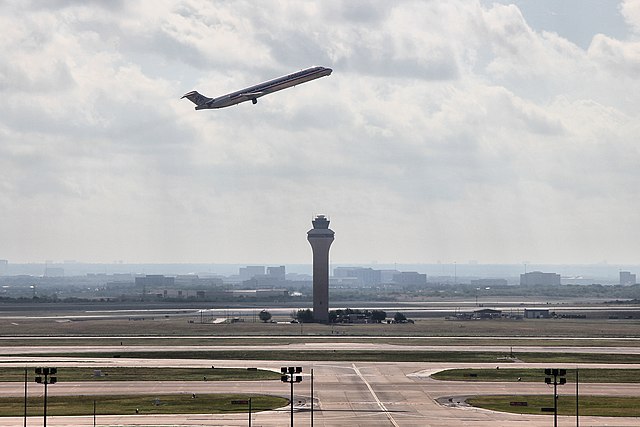 Air traffic control tower at Dallas/Fort Worth International Airport with a plane taking off
