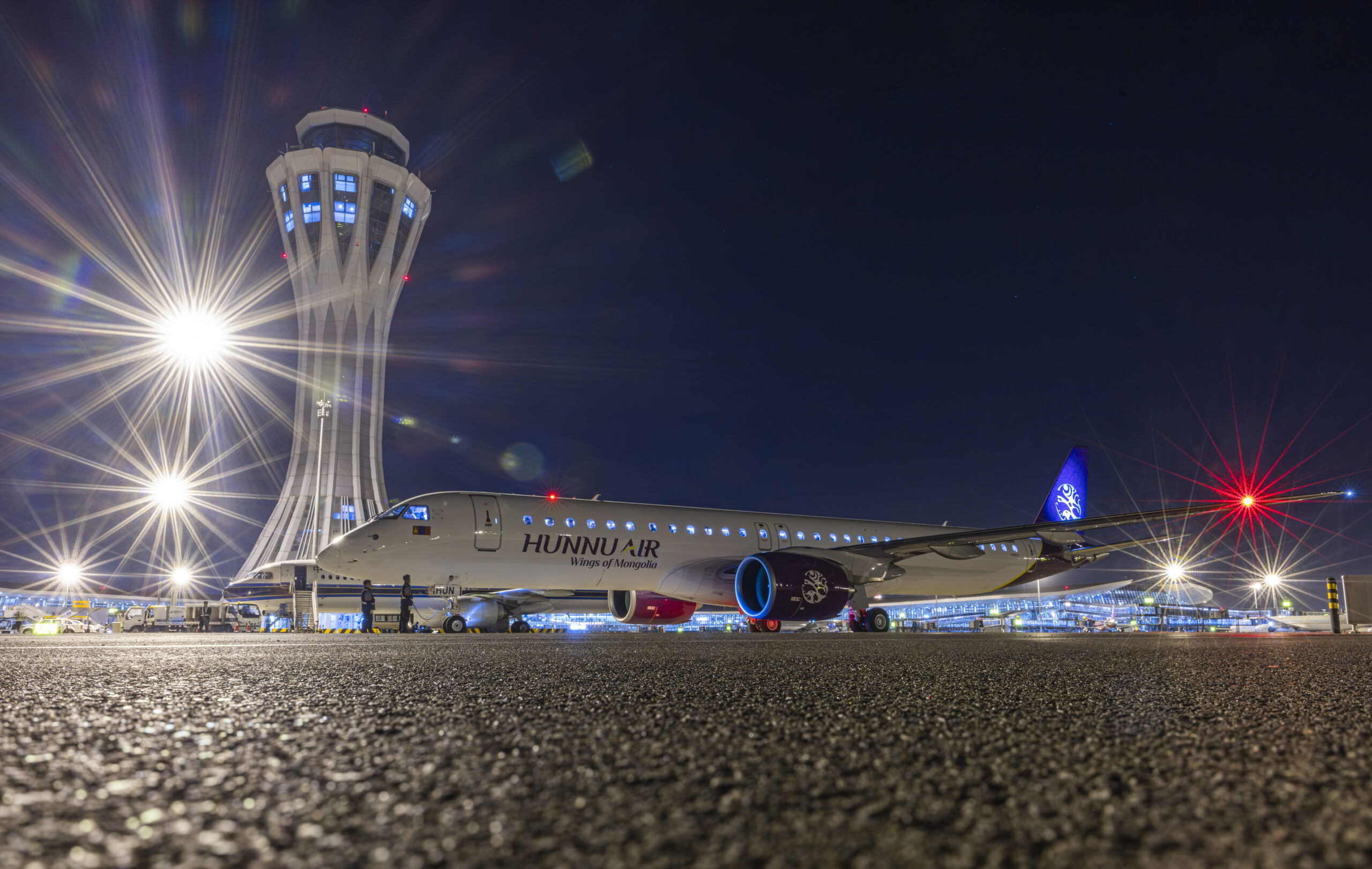 An image of Hunnu Air's new E195-E2 aircraft, stationary on the runway at Beijing Daxing Airport, China.