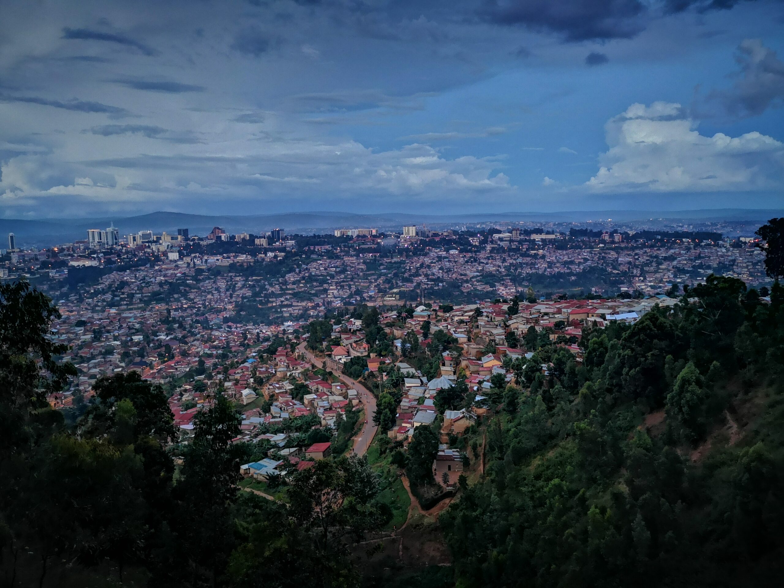 An image of a sweeping view of Kigali, Rwanda. There are skyscrapers in the distance where the city centre begins.