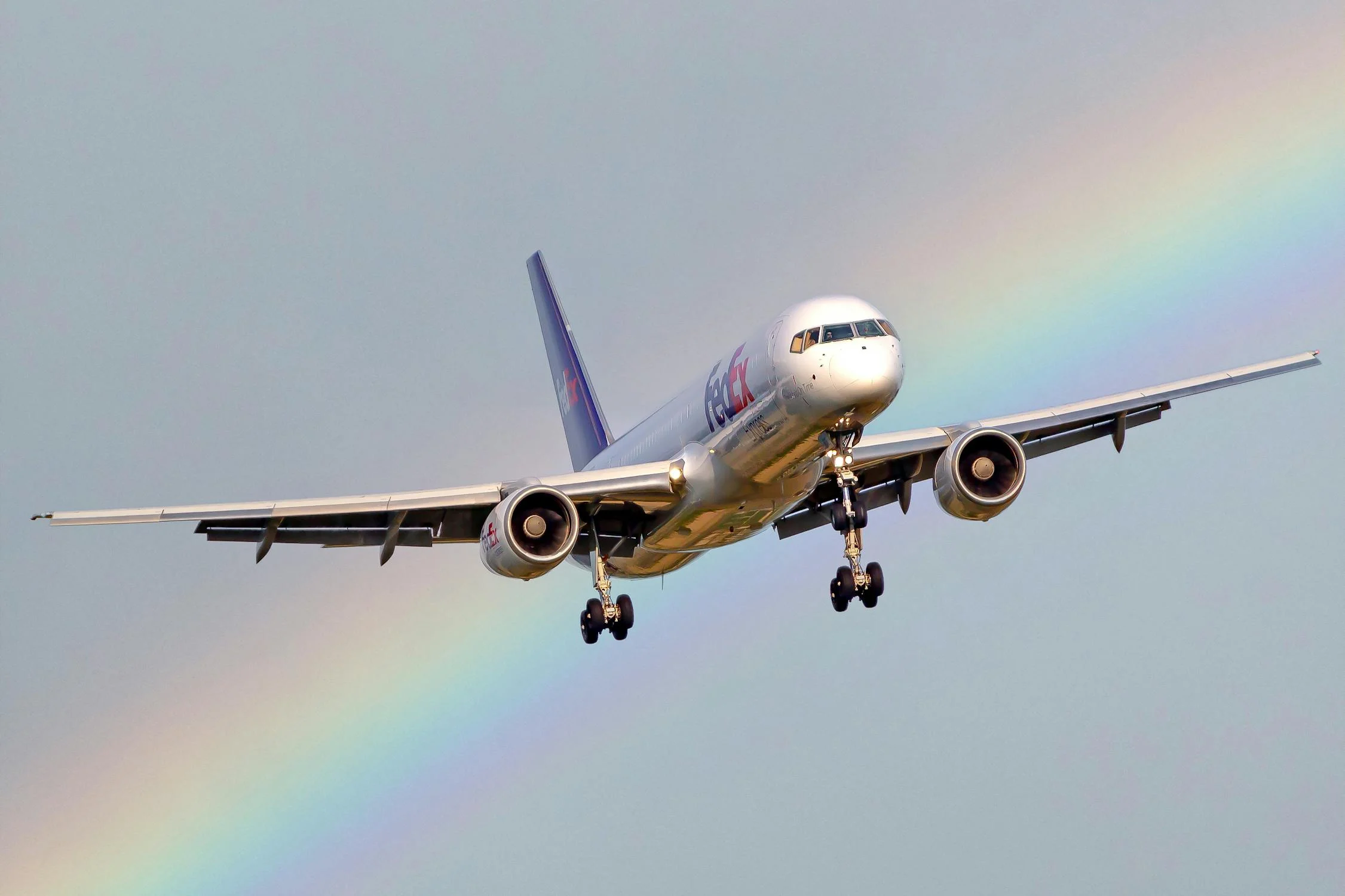 A photo of a Rainbow behind a FedEx Cargo Airplane