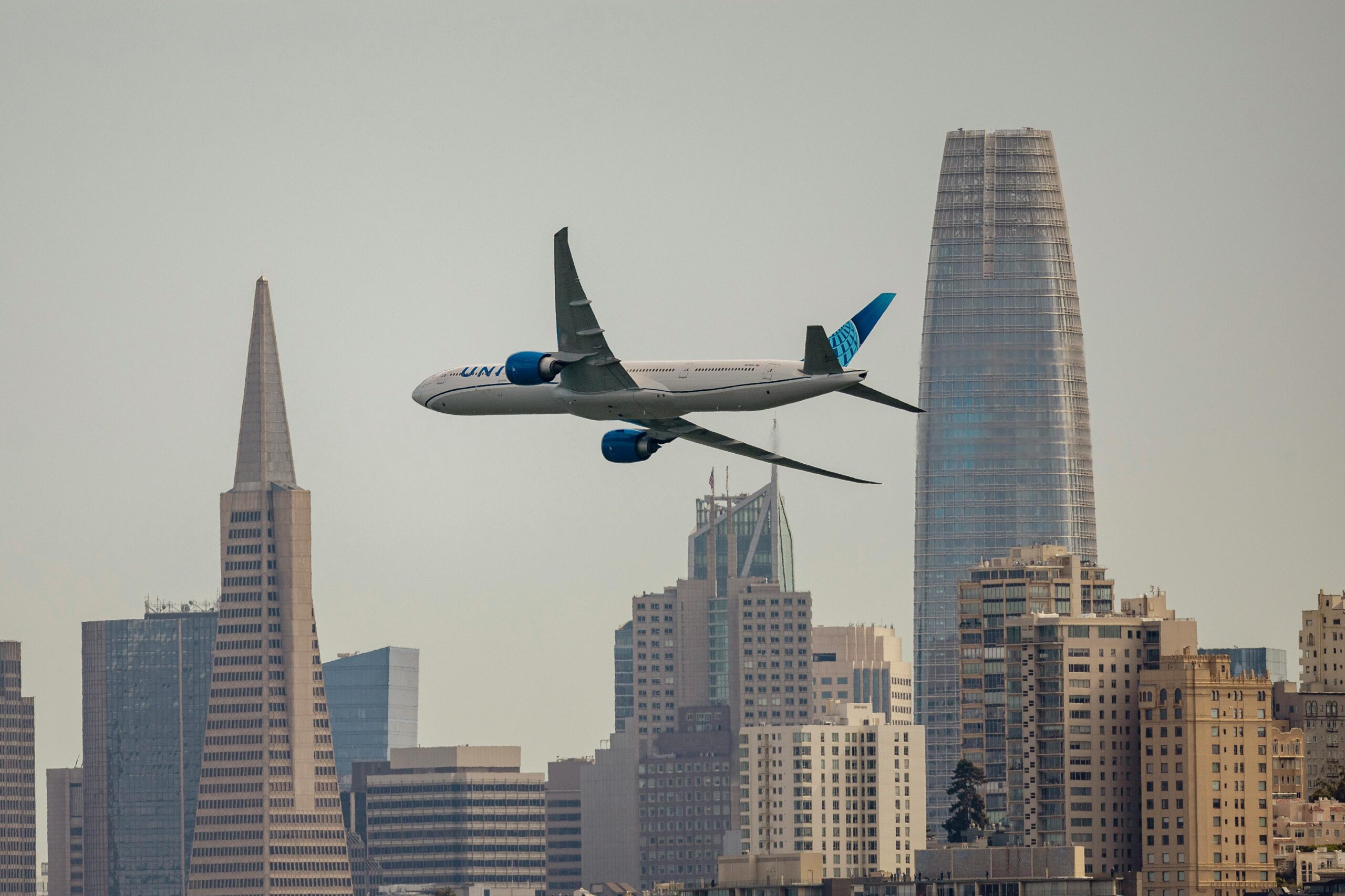 An image of a United Airlines aircraft flying over San Francisco's skyline