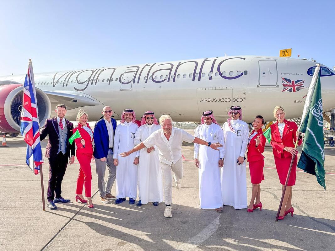 Sir Richard Branson and the crew celebrate in front of a Virgin Atlantic-operated aircraft.