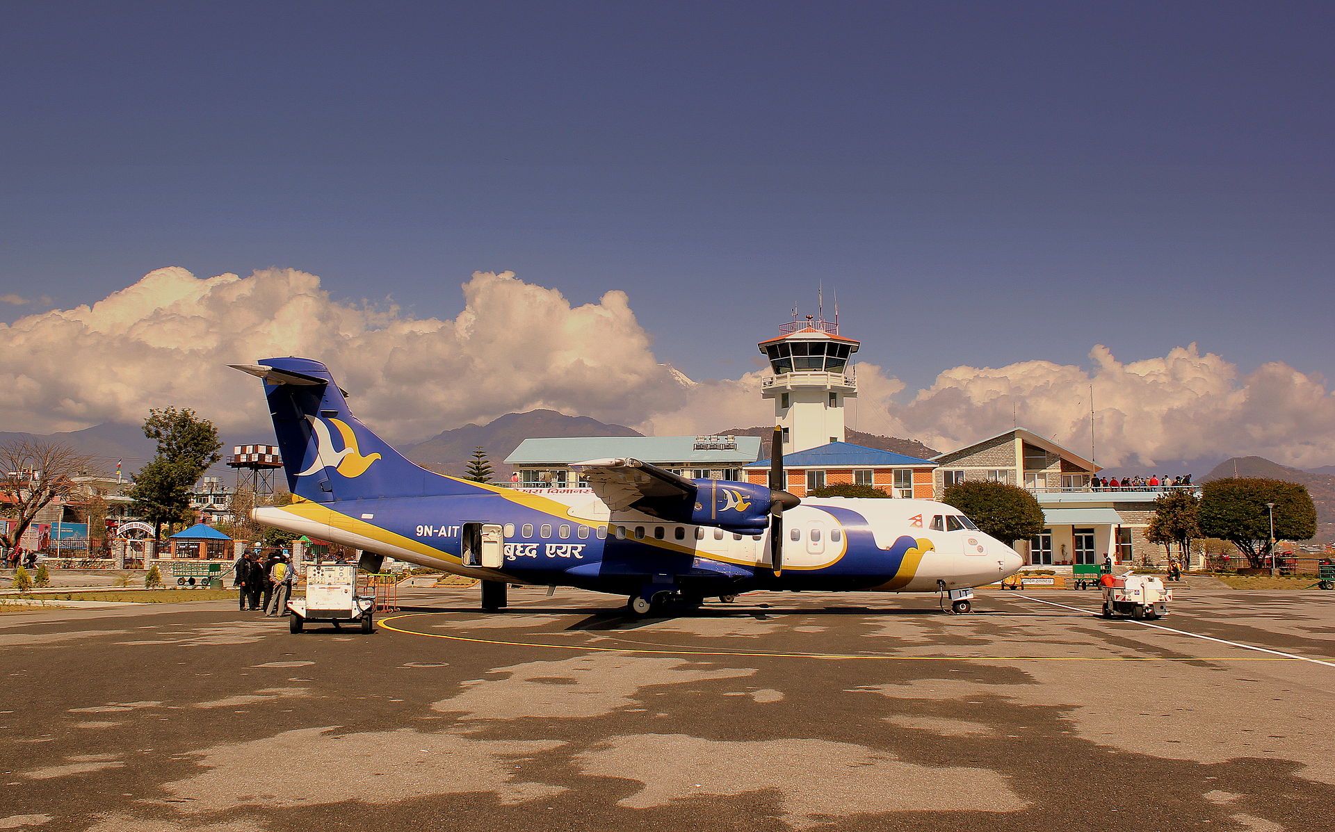 A picture of a Buddha Air plane at Pokhara Airport with mountains in the back