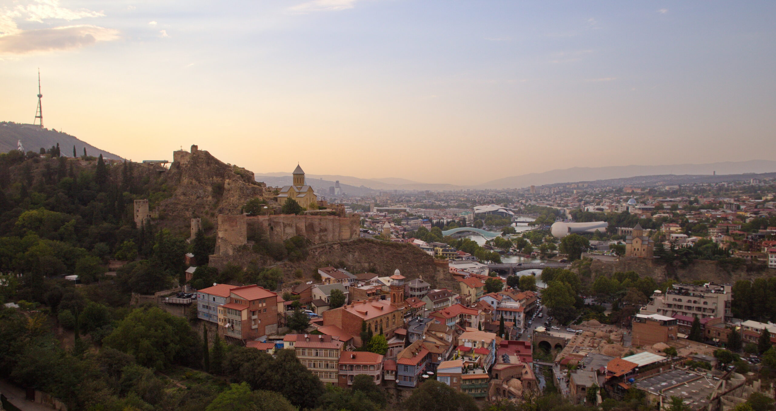 A panoramic view of the historical neighbourhoods from a hill in city of Tbilisi, Georgia with a sunset in the background.