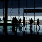 Silhouettes of people at the airport with aircrafts in the background