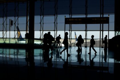 Silhouettes of people at the airport with aircrafts in the background