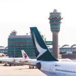 An airport with planes and air traffic control tower in the background