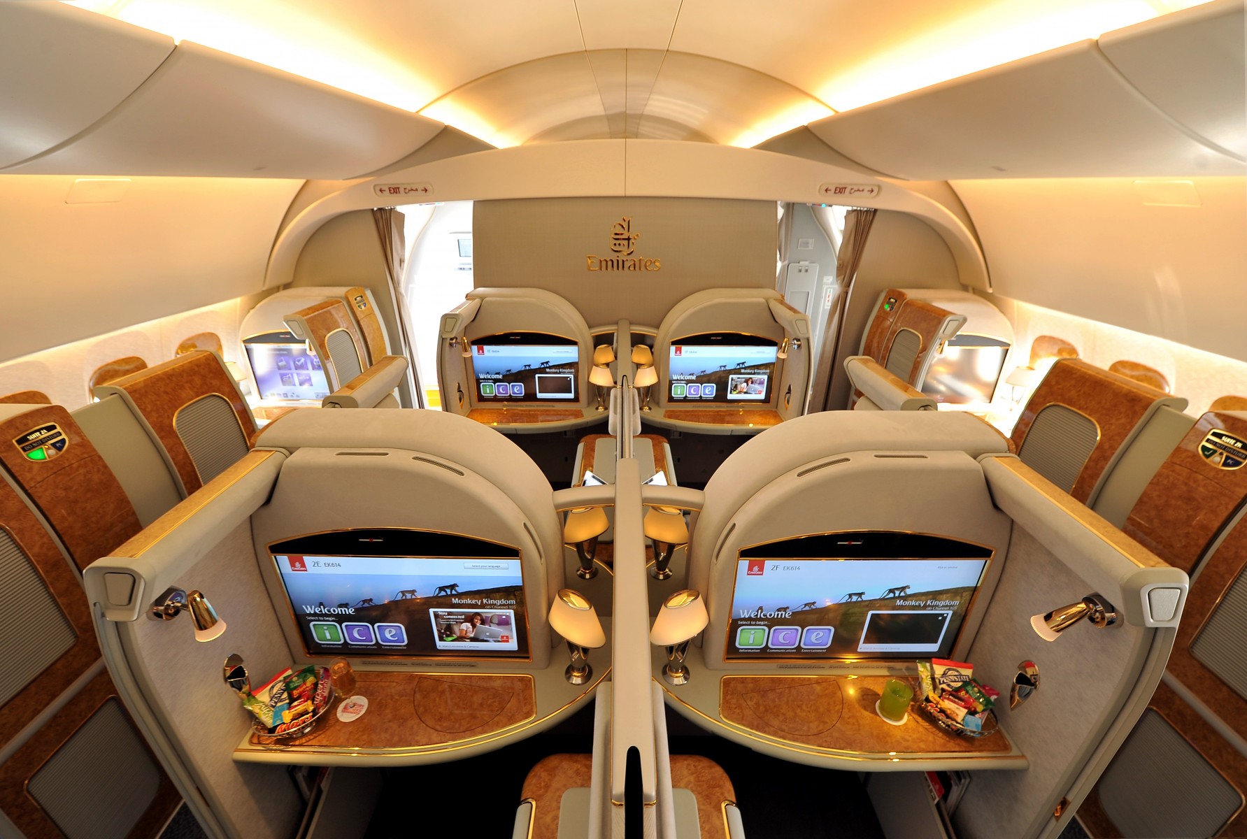 A luxury airline cabin interior featuring seating pods with large personal screens and amenities.
