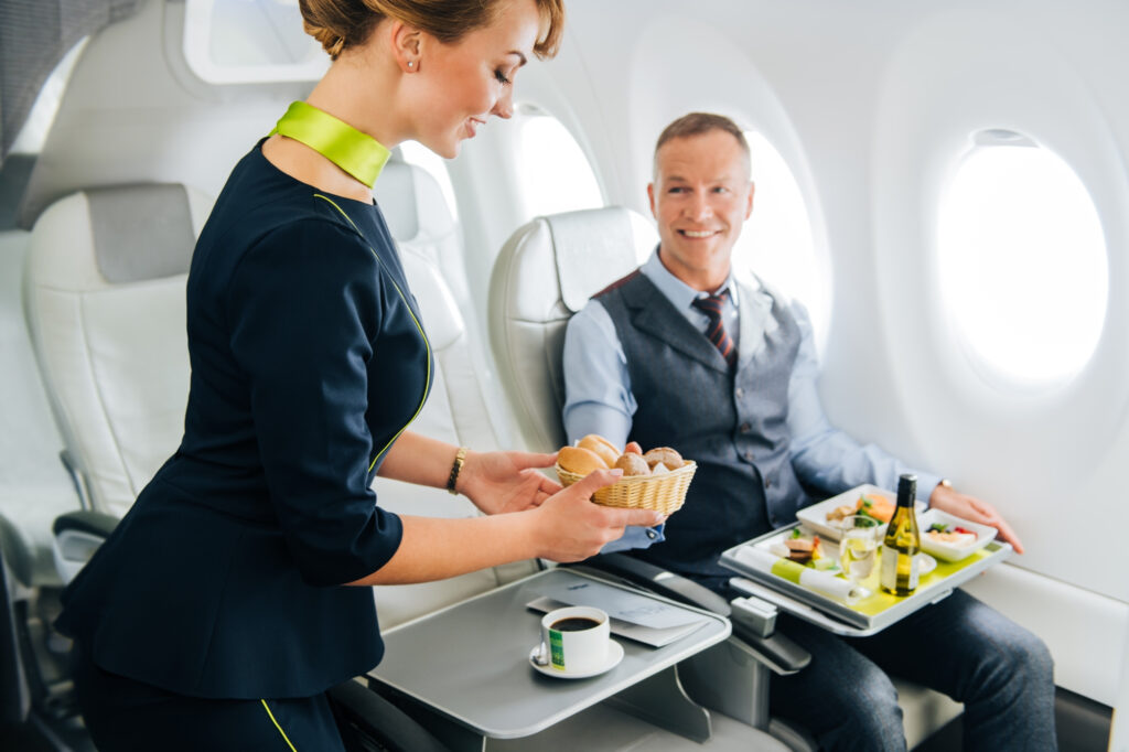 A female flight attendant presents food to a male passenger in an airBaltic aircraft.