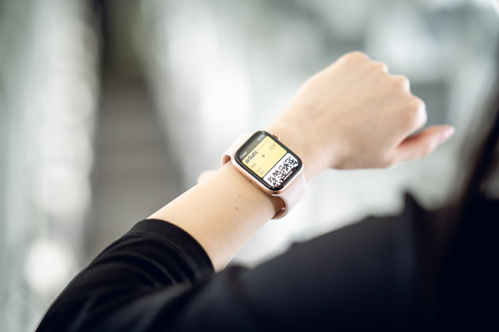 A woman wearing an Apple Watch on her wrist, is looking at the screen which is showing the airBaltic membership. 