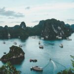 A stunning view of the serene Ha Long Bay, Vietnam, featuring green limestone islands and several boats cruising on the calm waters.