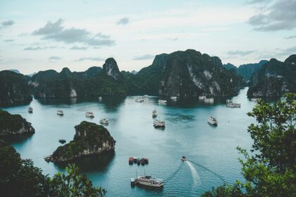 A stunning view of the serene Ha Long Bay, Vietnam, featuring green limestone islands and several boats cruising on the calm waters.