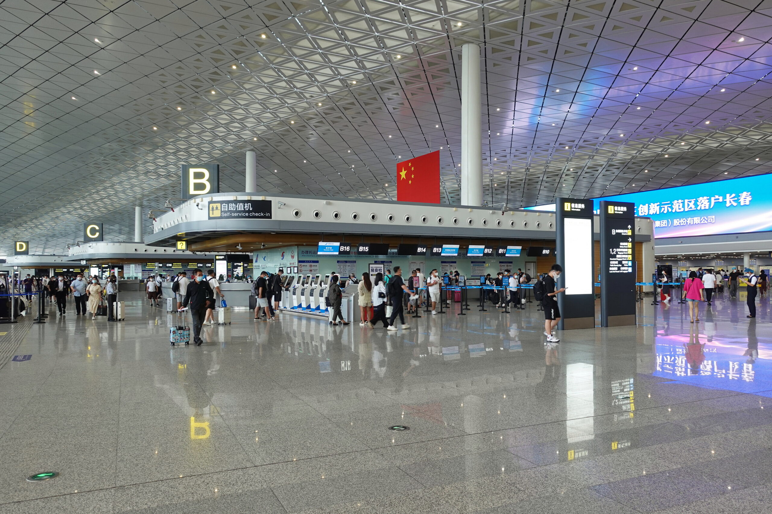 Terminal 2 of Changchun Airport in China. There is a row of check-in desks with the Chinese flag flown above.