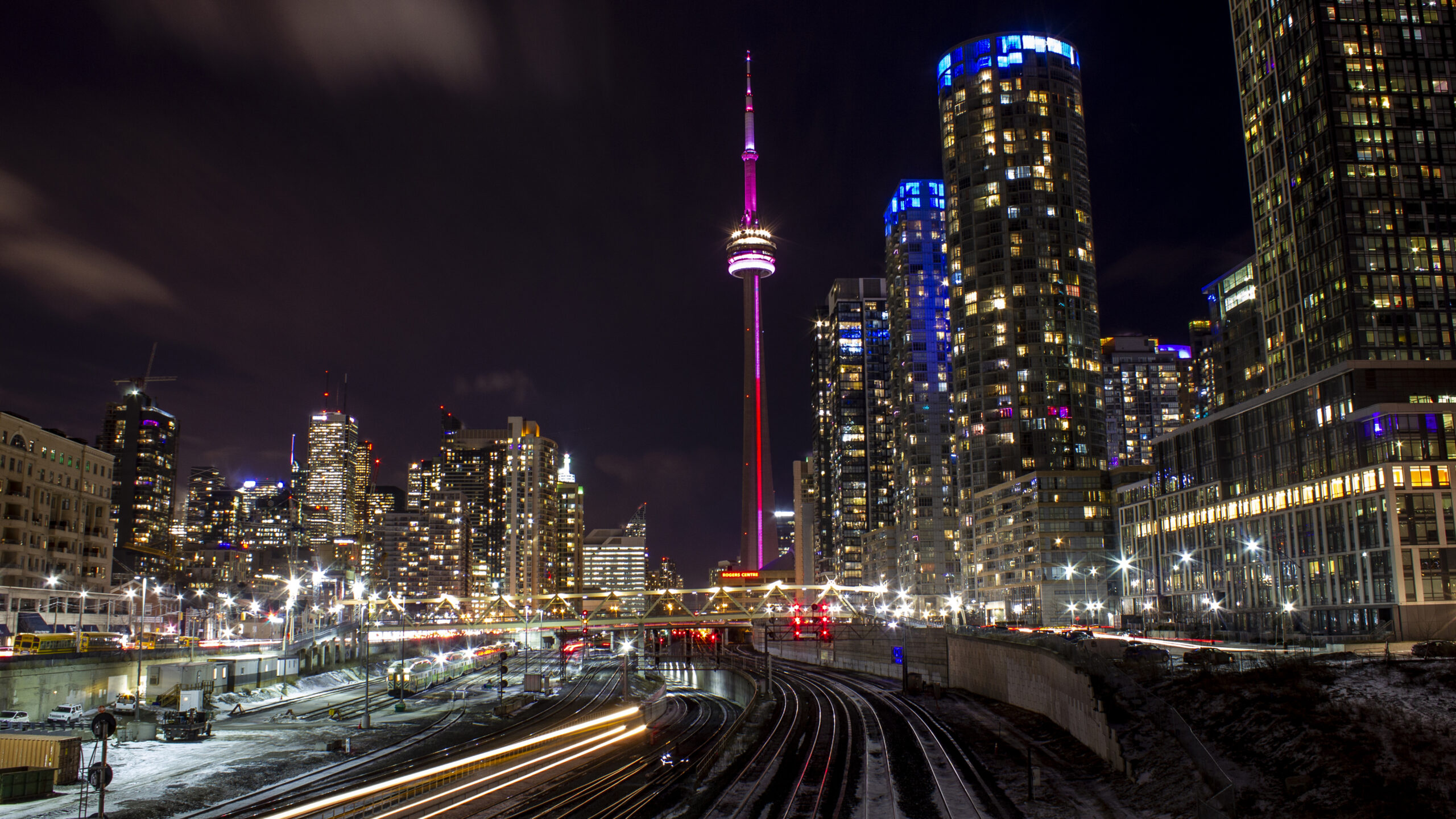 A view of downtown Toronto's iconic skyline at night, with city lights and tall skyscrapers visible.