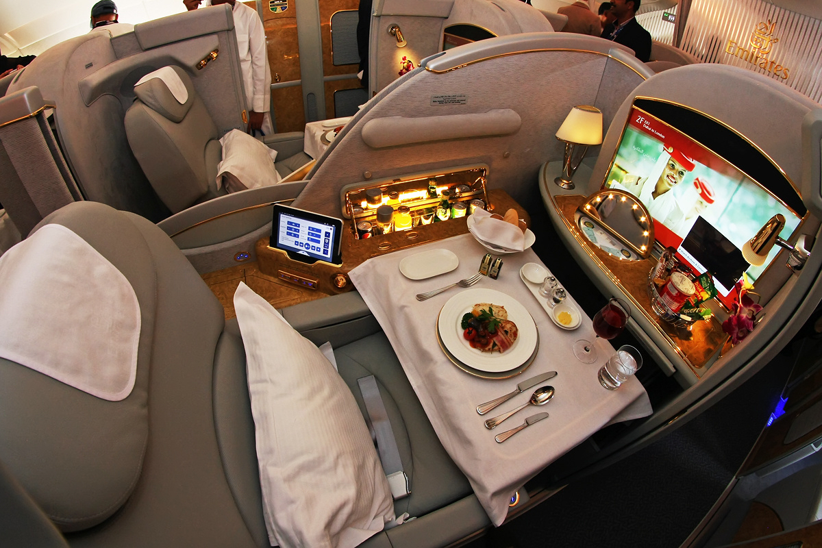 A luxurious First Class Private Suite on an Emirates flight, with dinner served and privacy screens closing the seat in.
