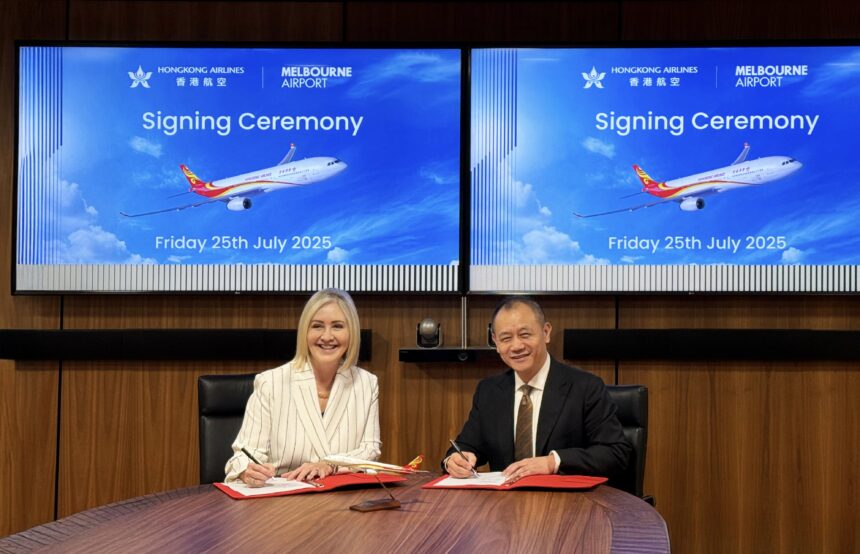 The representatives were attending the signing ceremony. Two individuals signing documents at a table, with a large screen displaying information displaying the aeroplane with the logo of Hong Kong Airlines in the background.