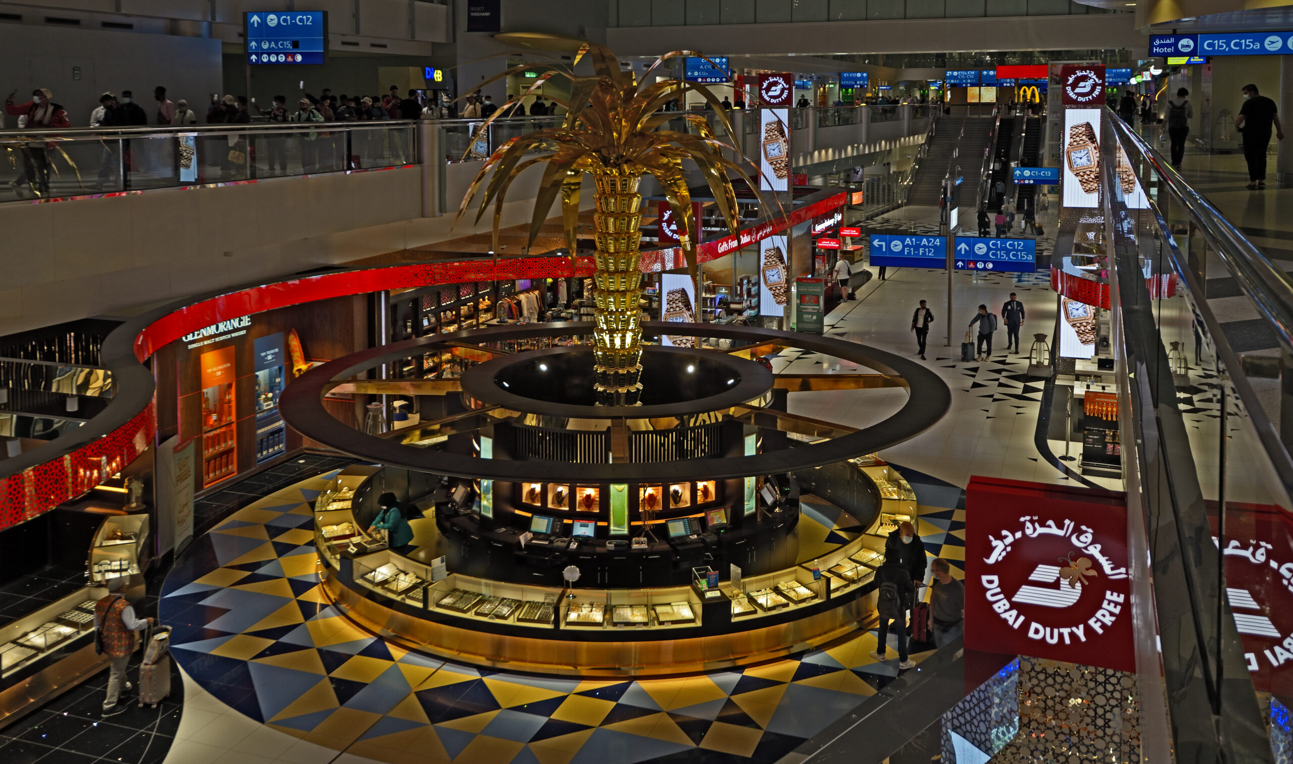 Dubai Airport Terminal 3, with a lit-up palm tree in the middle and duty-free shops lining the walls.