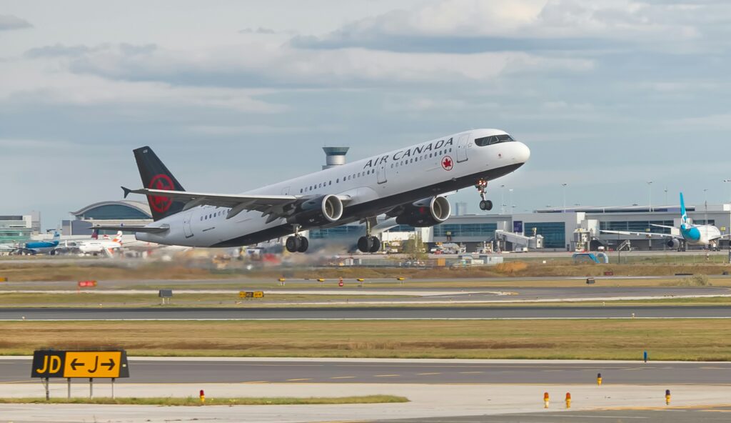 A large Air Canada jet is soaring through a clear blue sky