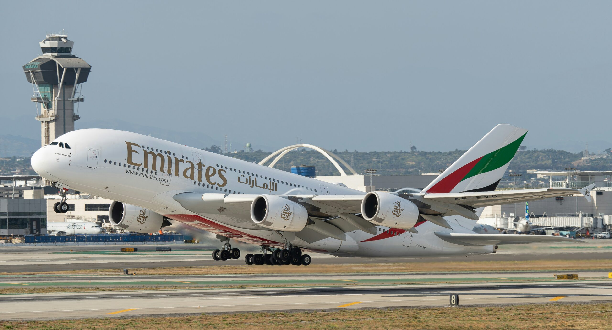 An Emirates A380 aeroplane takes off from the runway, showcasing its elegant design and vibrant logo.