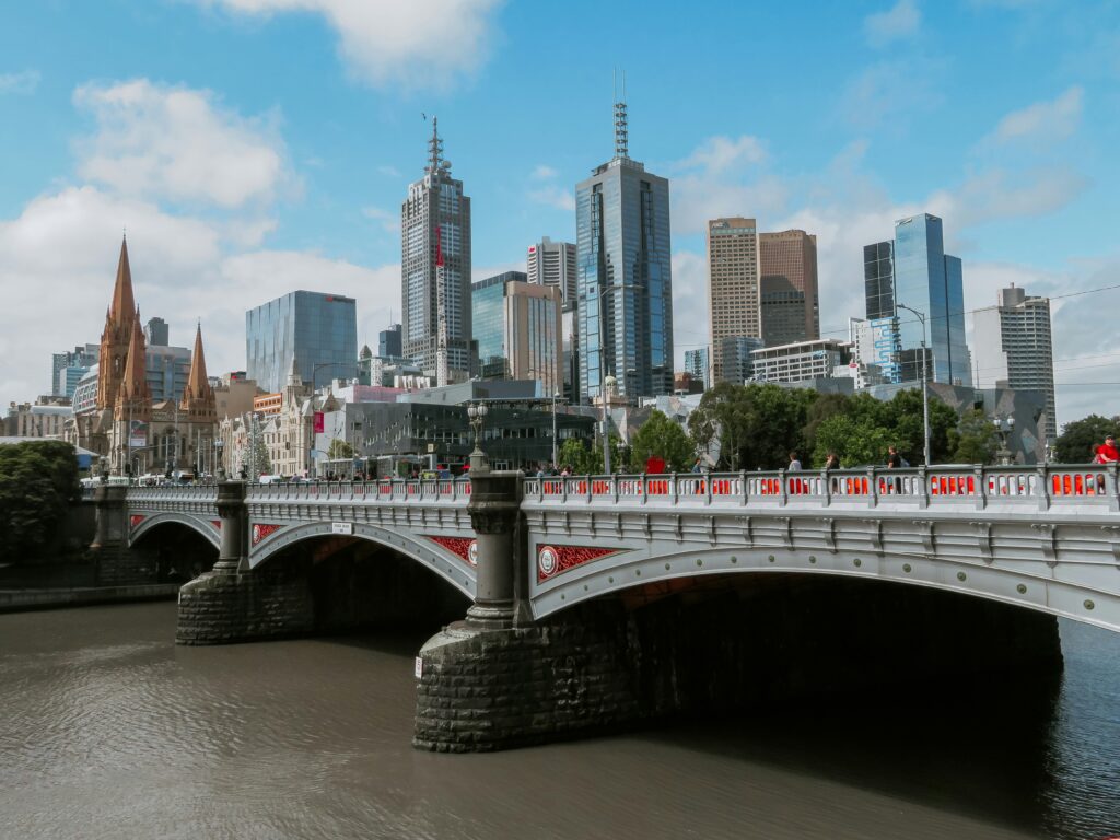 The view of Melbourne City. A bridge spans a river, with a city skyline visible in the background under a clear blue sky.