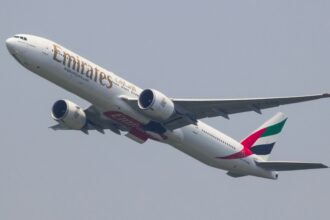 A Boeing 777 aeroplane from Emirates airline taking off and climbing into the sky.
