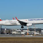 A Turkish Airlines white and red plane taking off, emphasizing its aerodynamic shape and bold color contrast.