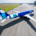 JetBlue Airbus A321 aircraft in bright blue livery parked on a tarmac at an airport.