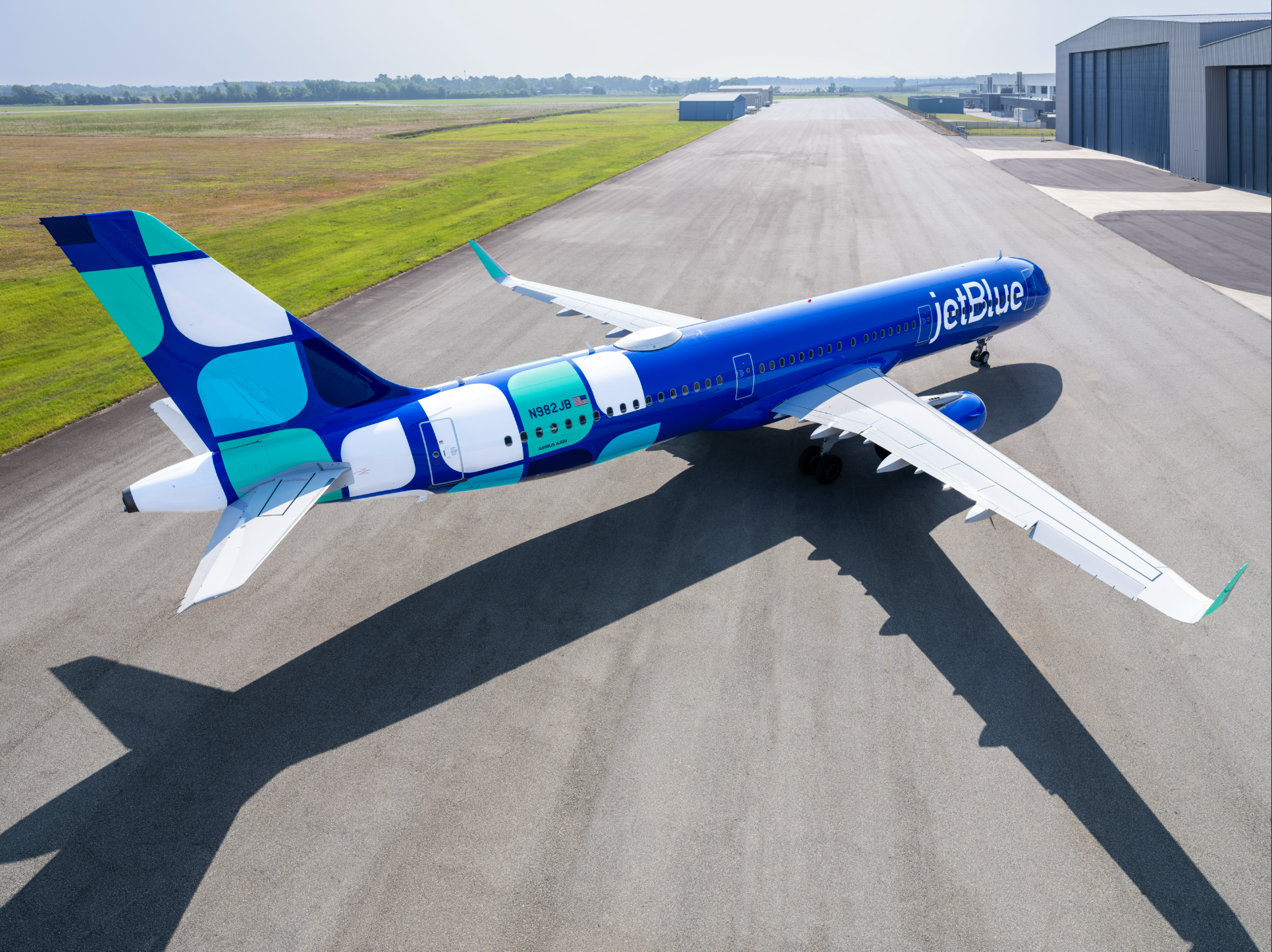 JetBlue Airbus A321 aircraft in bright blue livery parked on a tarmac at an airport.