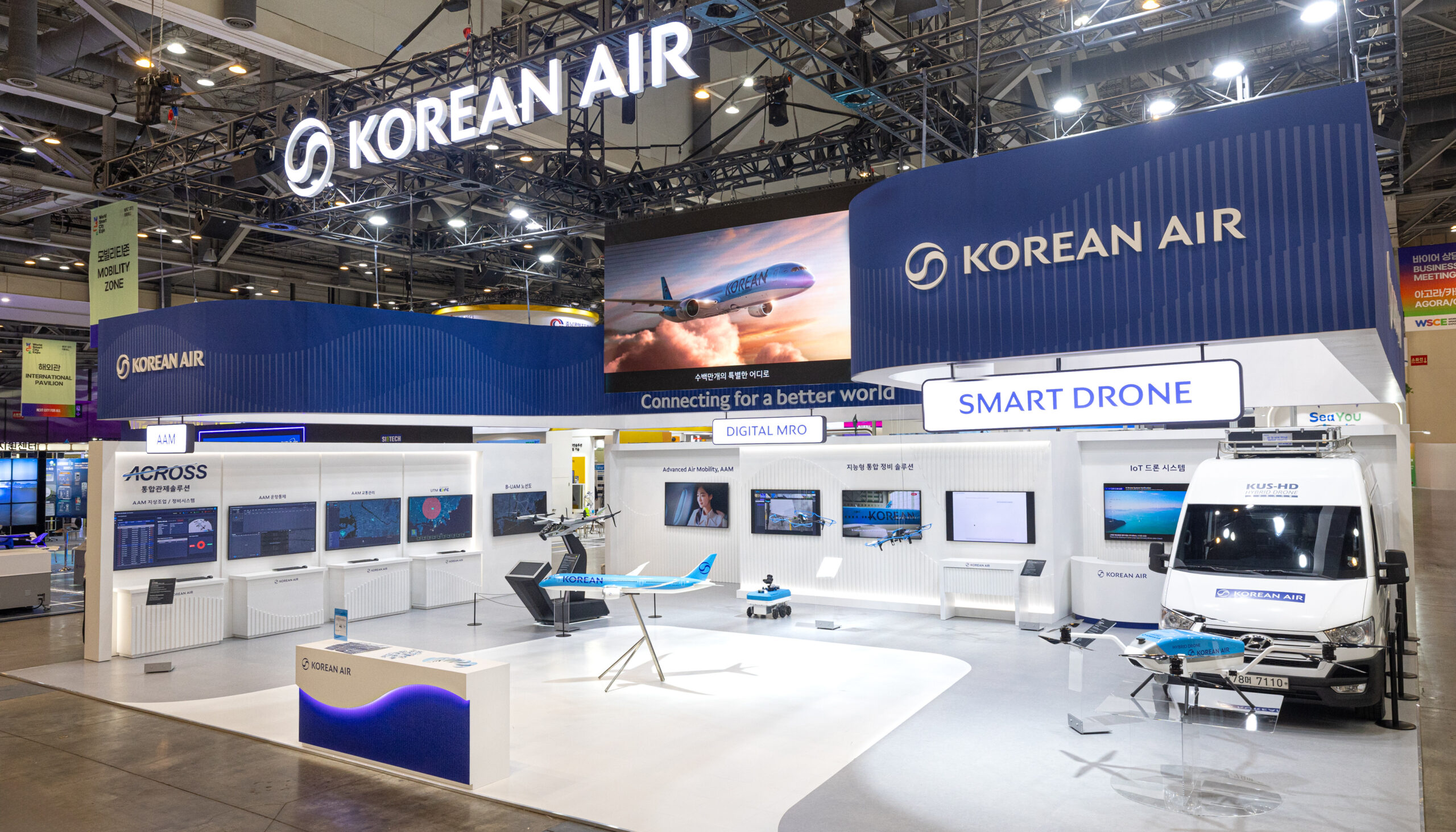 Exhibition booth for Korean Air showcasing Smart Drone technology. Features a drone on a platform, screens with data, and a model aeroplane.
