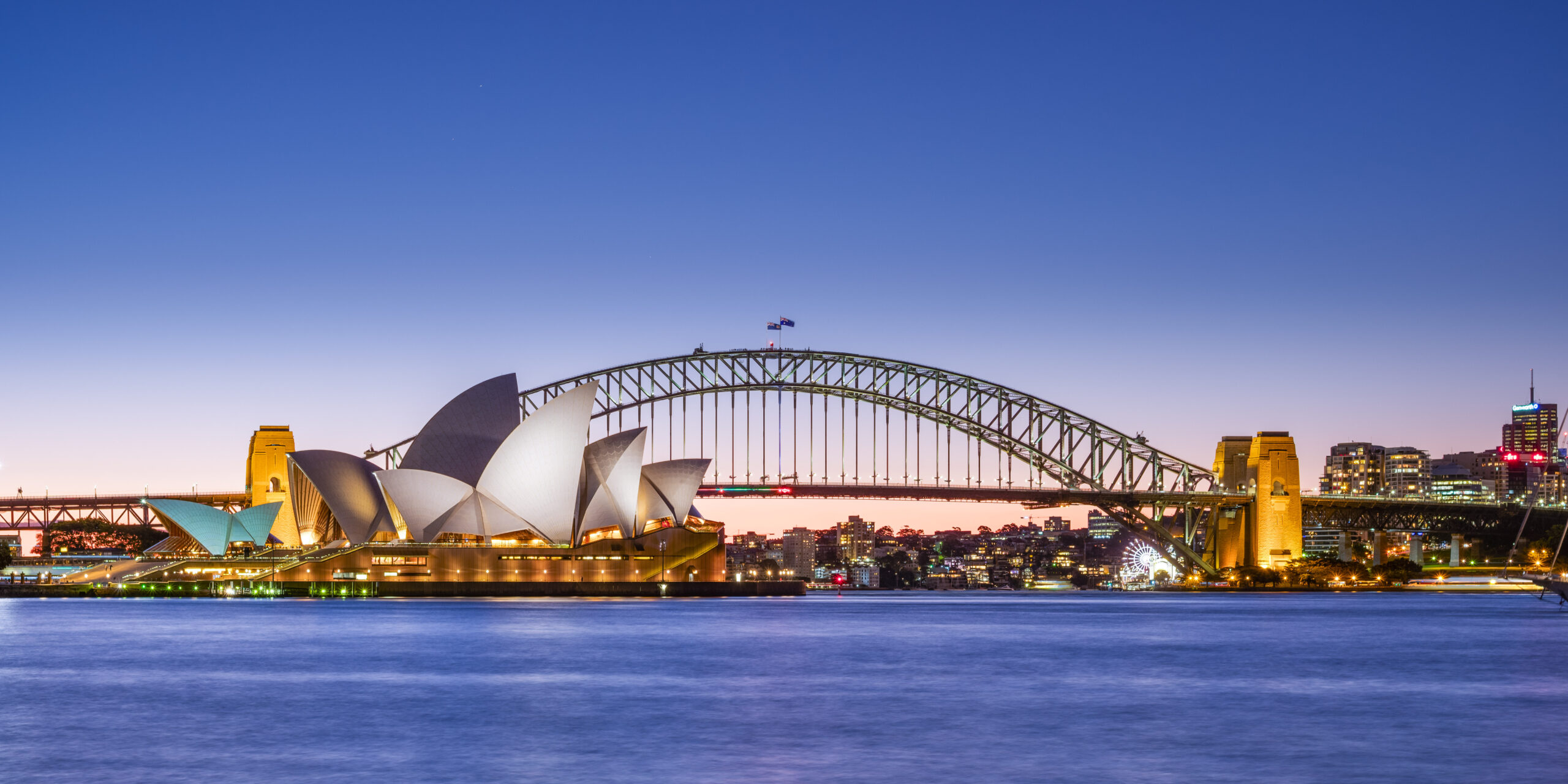 An image of Sydney's Opera House, Harbour Bridge and Central Business District lit up at dusk.