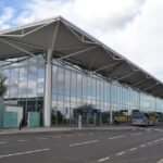 The outside of the Bristol Airport terminal building, with a bus parked outside the entrance to Departures.