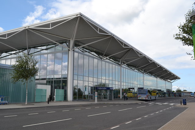The outside of the Bristol Airport terminal building, with a bus parked outside the entrance to Departures.