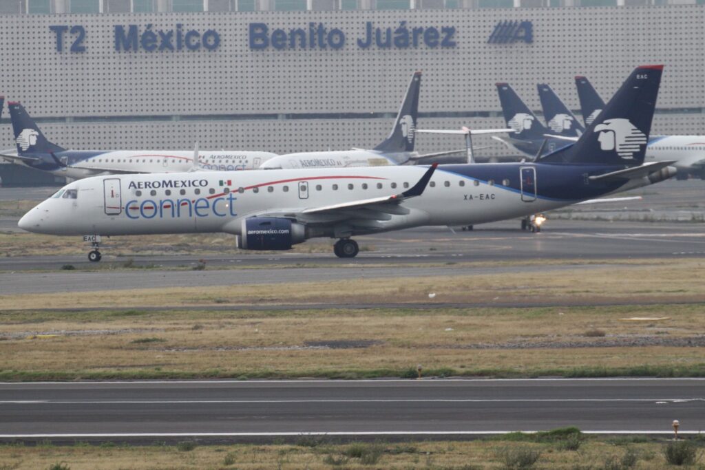 Aeromexico E190 aircraft on the tarmac at Mexico City International Airport, with several other Aeromexico planes visible in the background.