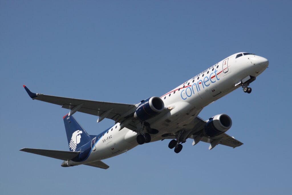 White Aeromexico E-190 jet taking off from at At Guatemala La Aurora International with plain blue sky in the background.