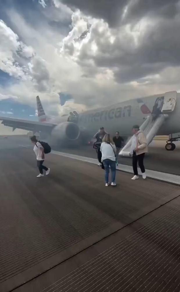 Passengers evacuate an American Airlines jet via emergency slides as smoke surrounds the aircraft on the runway. After mechanical incident.