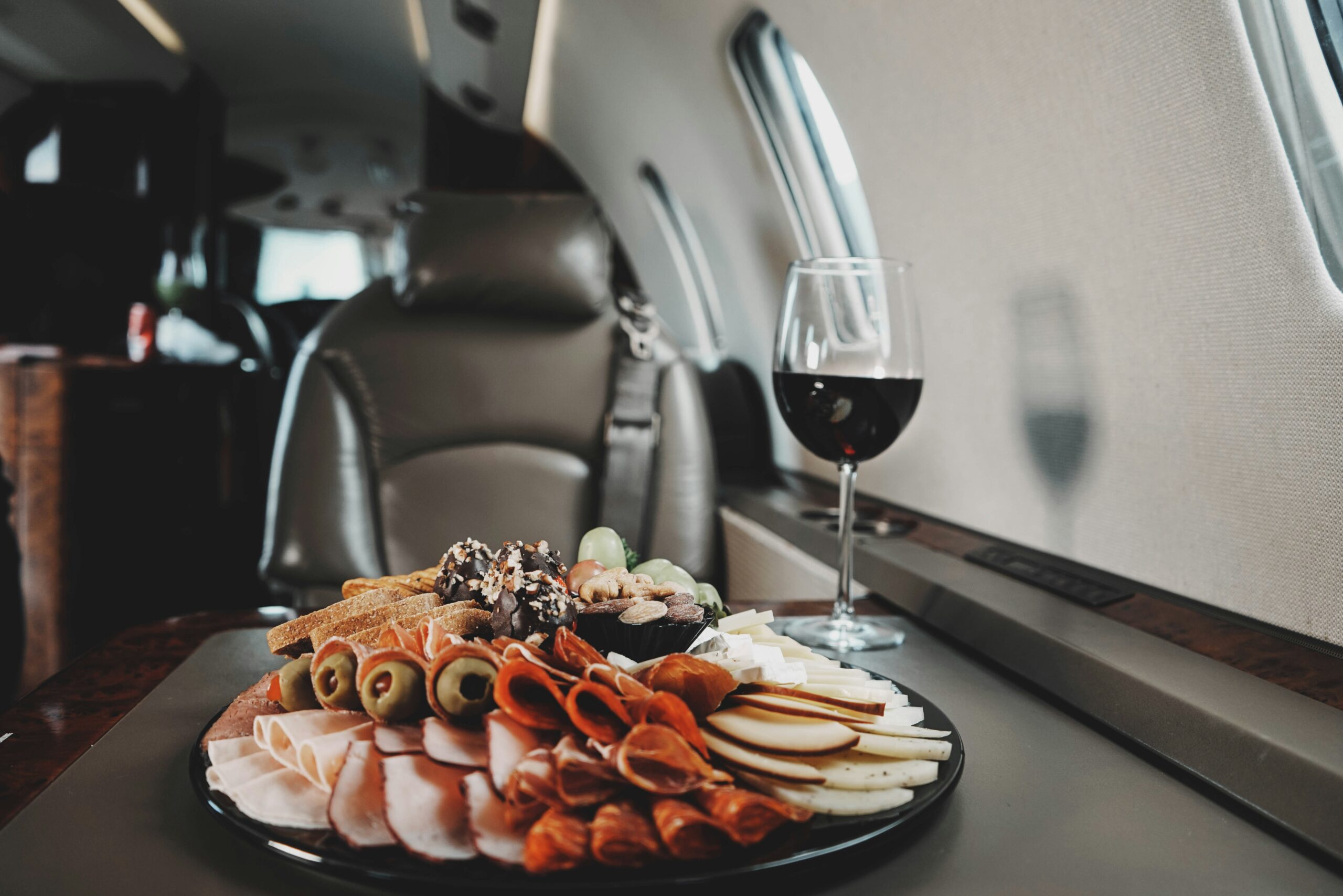 A plate of food and a glass of wine on a table in a private jet cabin