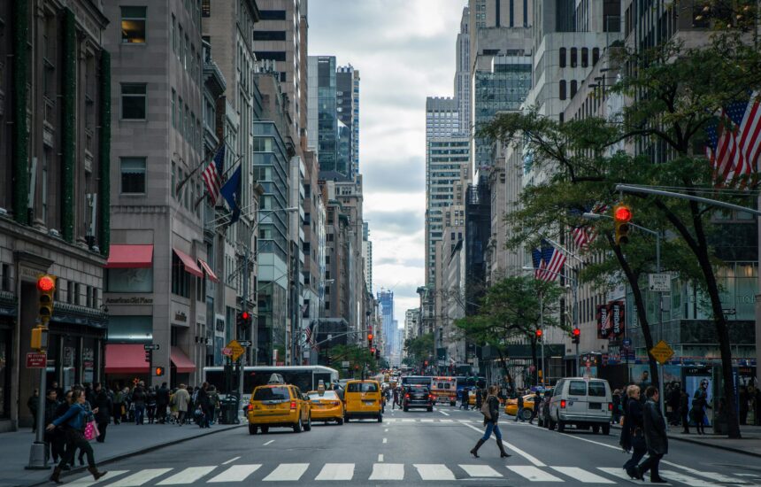 A busy street in New York with people crossing the road and traffic in the background