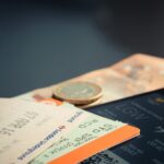Flight ticket on a phone screen, train tickets and some cash