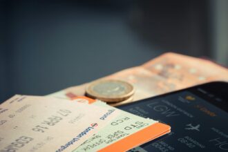Flight ticket on a phone screen, train tickets and some cash