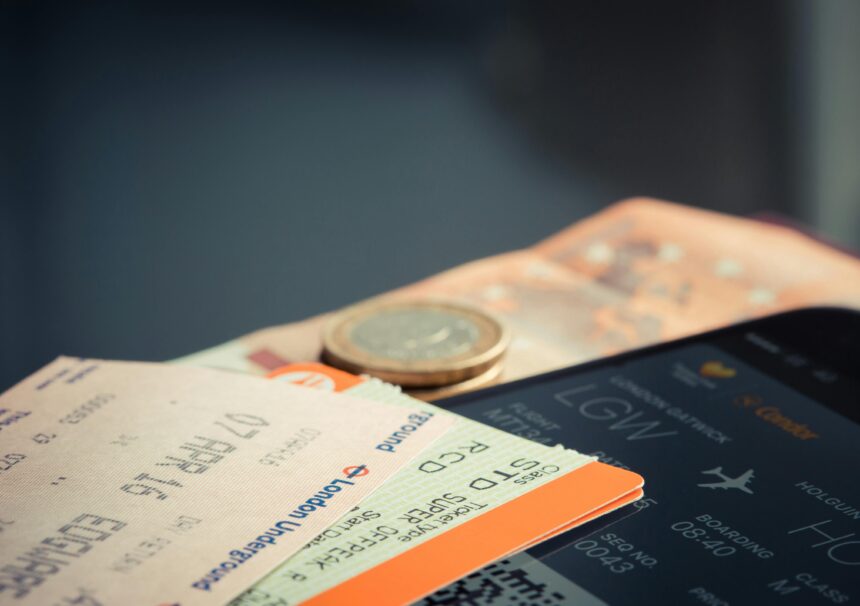 Flight ticket on a phone screen, train tickets and some cash