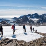 A group of people hiking through snowy Greenlad using ropes