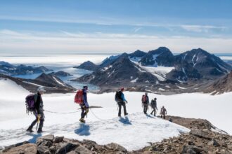 A group of people hiking through snowy Greenlad using ropes