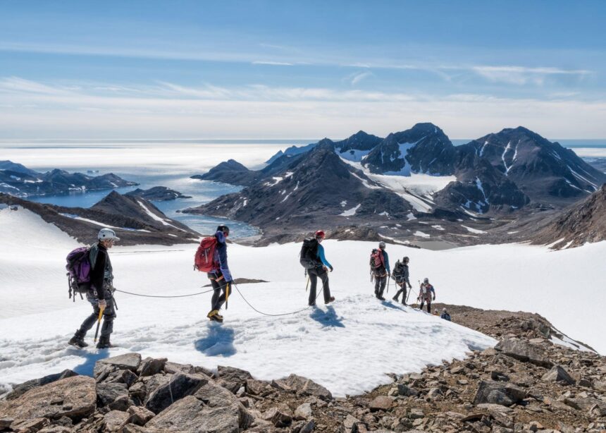 A group of people hiking through snowy Greenlad using ropes