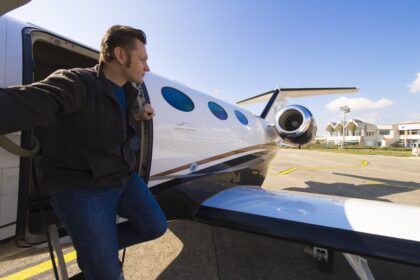 Man stepping out from a private jet under a clear blue sky. Climate