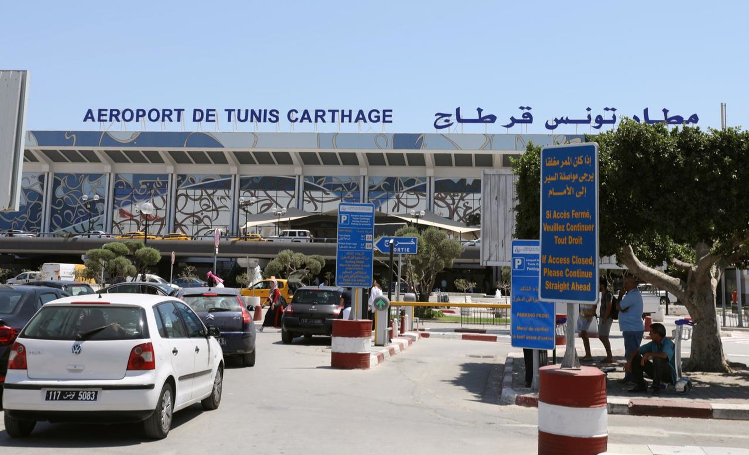 Image shows the entrance to Tunis Carthage Airport with cars parked and queuing to enter in daylight hours